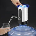 Hand pressing a button on a water dispenser with a glass being filled.
