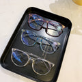 Three pairs of eyeglasses on a black tray