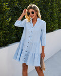 Woman wearing a blue checkered dress with sunglasses outdoors.