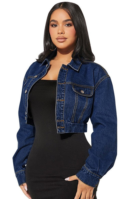 Woman wearing a blue denim jacket over a black dress on a white background