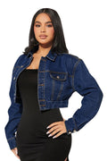 Woman wearing a blue denim jacket over a black dress on a white background