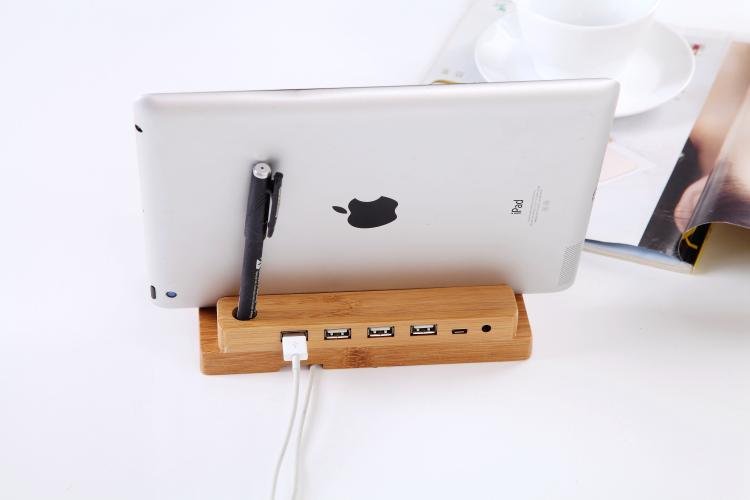 Wooden stand with USB ports holding an Apple iPad on a white surface.