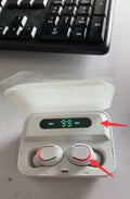 Wireless earbuds in a charging case with a digital display on a desk.