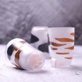 Two cylindrical containers with animal print designs on a gray surface.