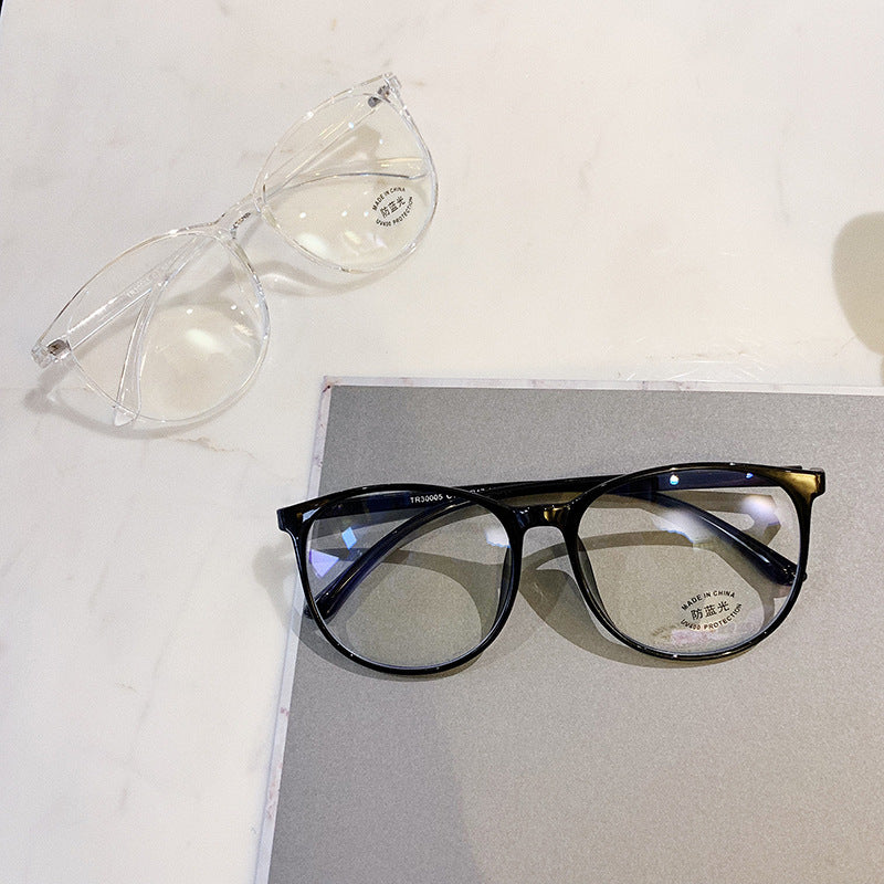 Black-framed eyeglasses on a white surface with a clear pair of sunglasses.