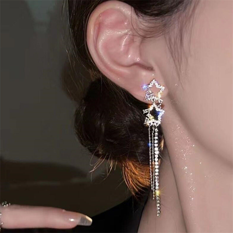 Close-up of an ear with a decorative earring featuring beads and feathers.
