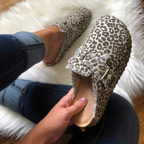 Leopard print loafers with embellishments on a fluffy white surface