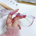 Hand holding a pair of pink sunglasses on a magazine background