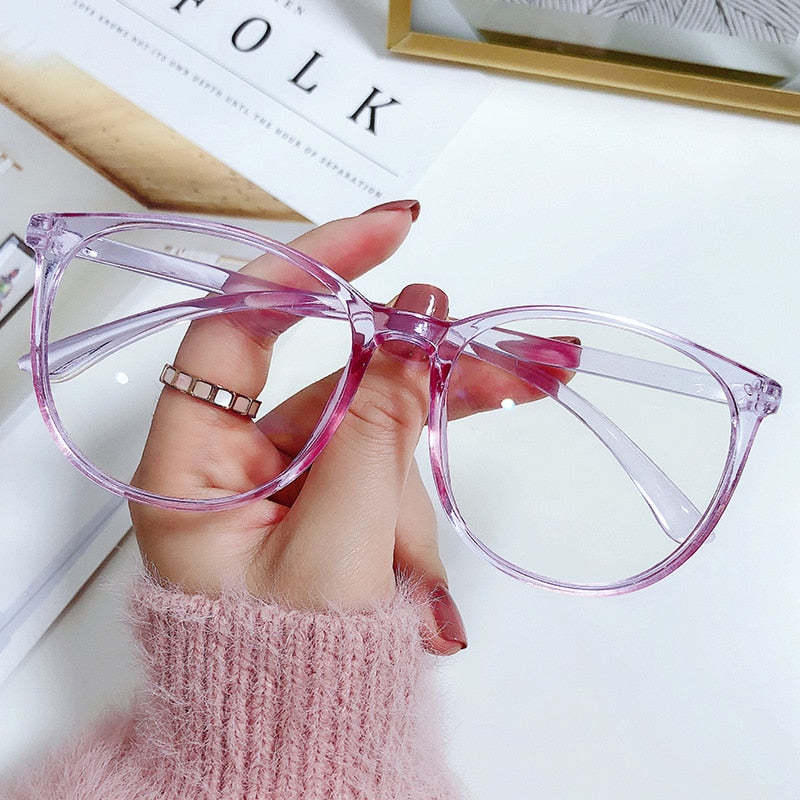 Hand holding a pair of pink sunglasses on a magazine background