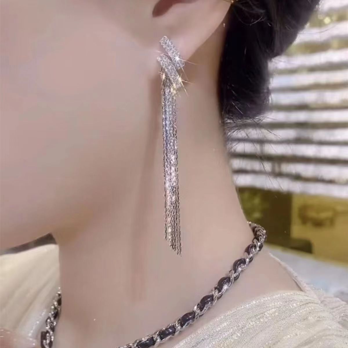 Close-up of a person wearing a long, dangling earring