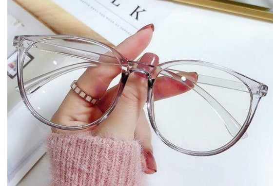 Clear cat-eye glasses held by a hand with pink nail polish 