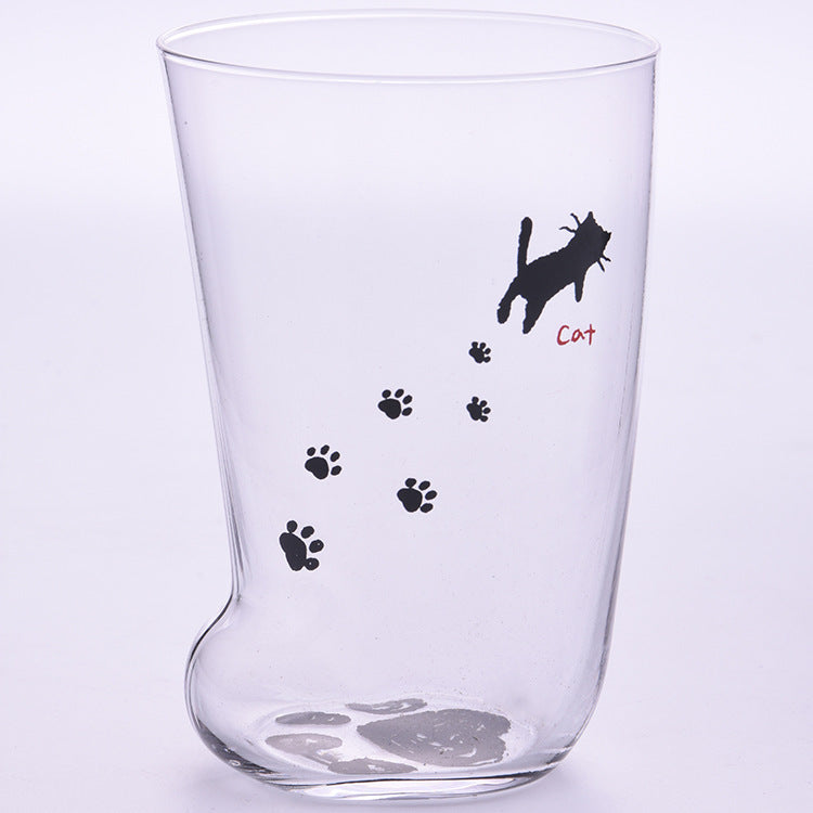 Clear glass tumbler with black paw prints and a cat illustration on a light purple background