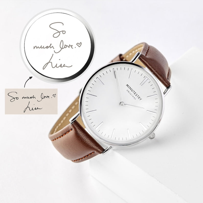 Watch with brown leather strap and white face on a light gray background