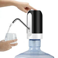 Hand filling a glass with water from a black and white water dispenser.