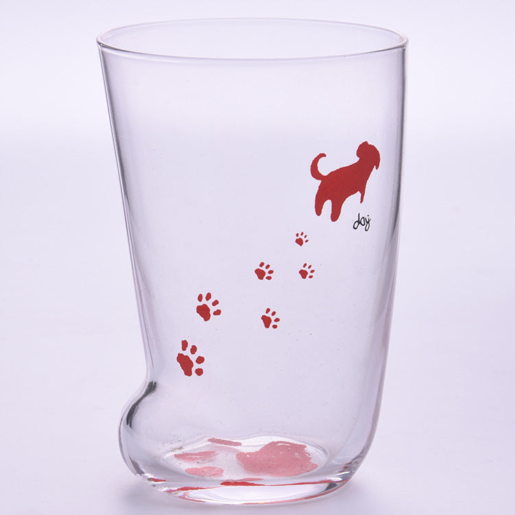 Clear glass tumbler with red dog and paw print design on a light purple background